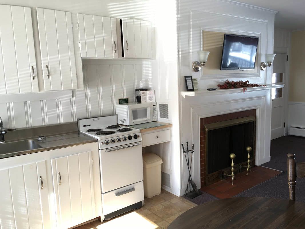 A kitchen with white cabinets, a stove, a microwave, and a fireplace.