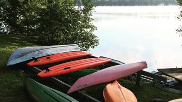 Une rangée de kayaks était alignée sur une rive herbeuse, au bord d’un lac paisible.