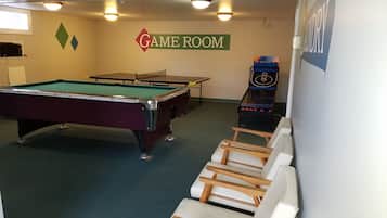 A game room with a pool table, a ping pong table, and a table tennis table.