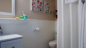 A bathroom with a toilet, a sink with a mirror, and two floral wall art pieces.