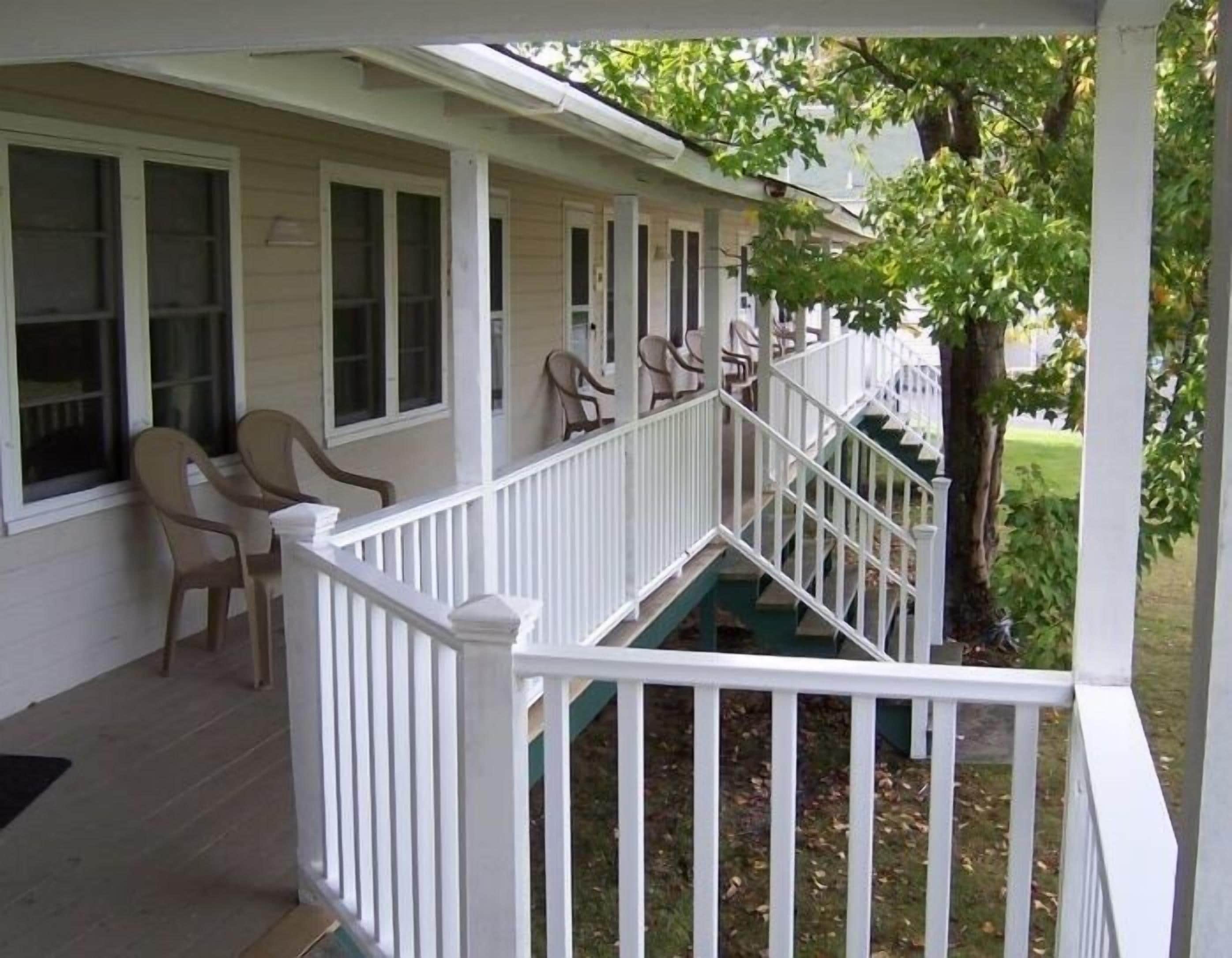 A covered porch with white railings and multiple windows.