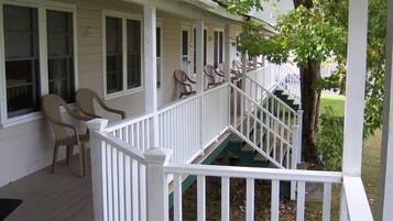A covered porch with white railings and multiple windows.