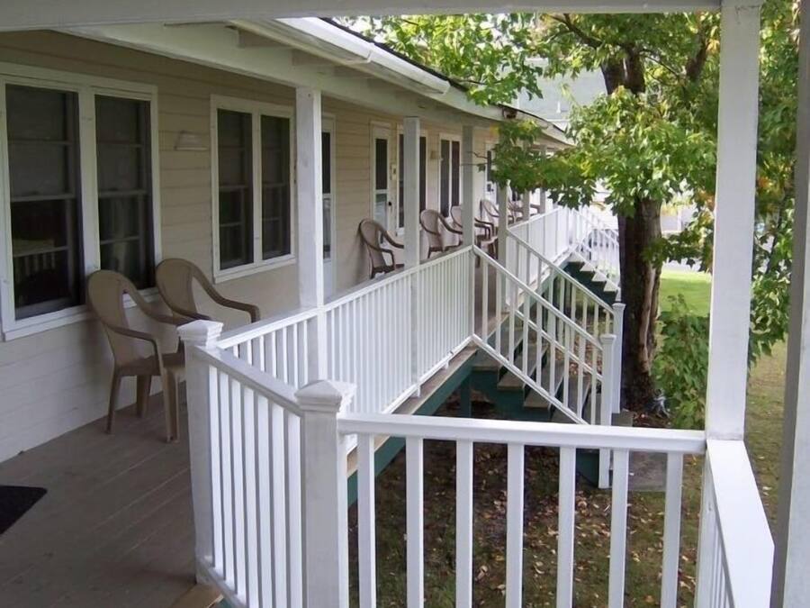A covered porch with white railings and multiple windows.