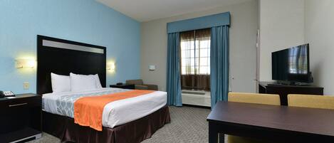 Une chambre d’hôtel avec un lit, un bureau, une télévision et une fenêtre avec des rideaux.