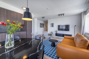 A modern living room with a black dining table, a sofa, and a TV.
