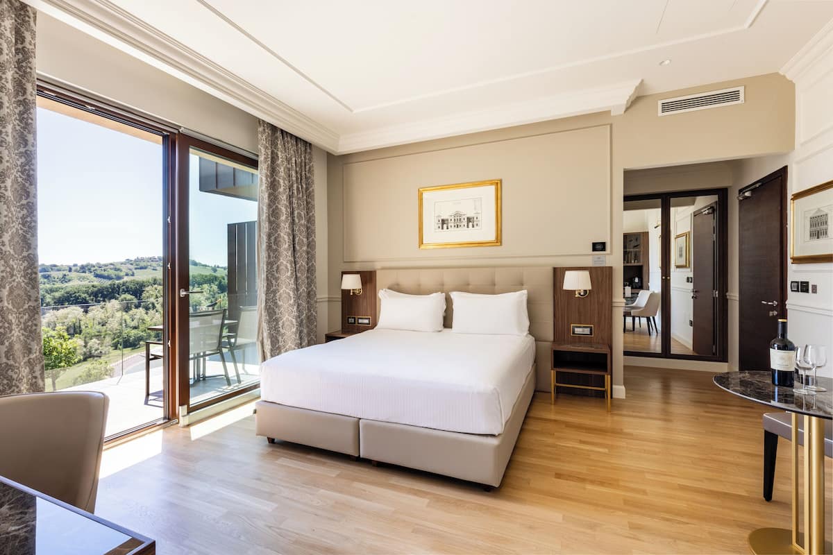 Ein geräumiges Schlafzimmer mit einem großen Bett, einem Essbereich und Blick ins Freie.