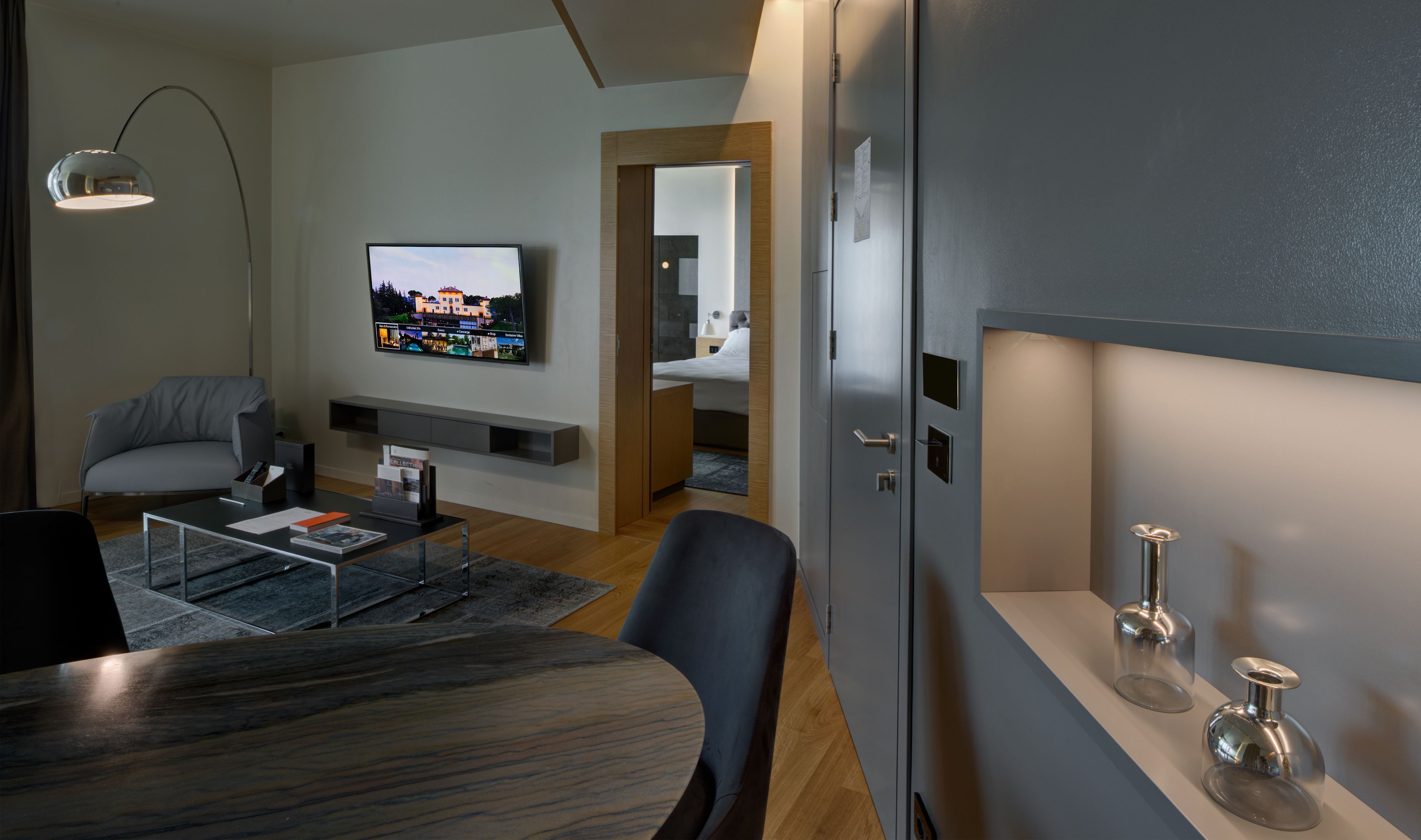 A modern living room with a flat-screen TV, a sofa, a coffee table, and a dining table.