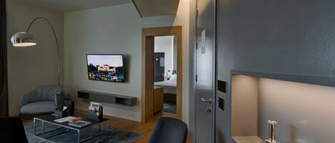 A modern living room with a flat-screen TV, a sofa, a coffee table, and a dining table.