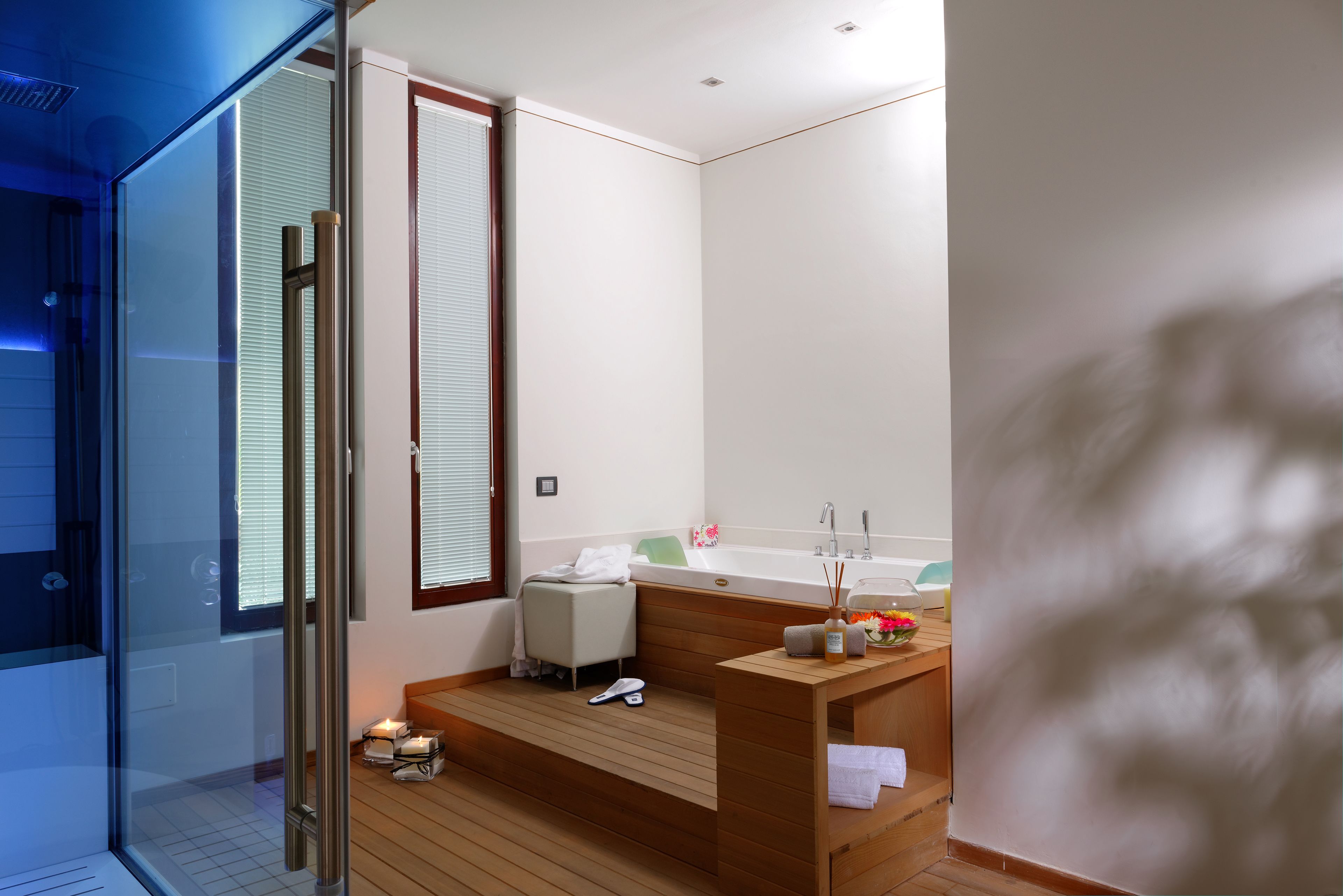 A modern bathroom with a glass shower enclosure, a wooden vanity, and a bathtub.