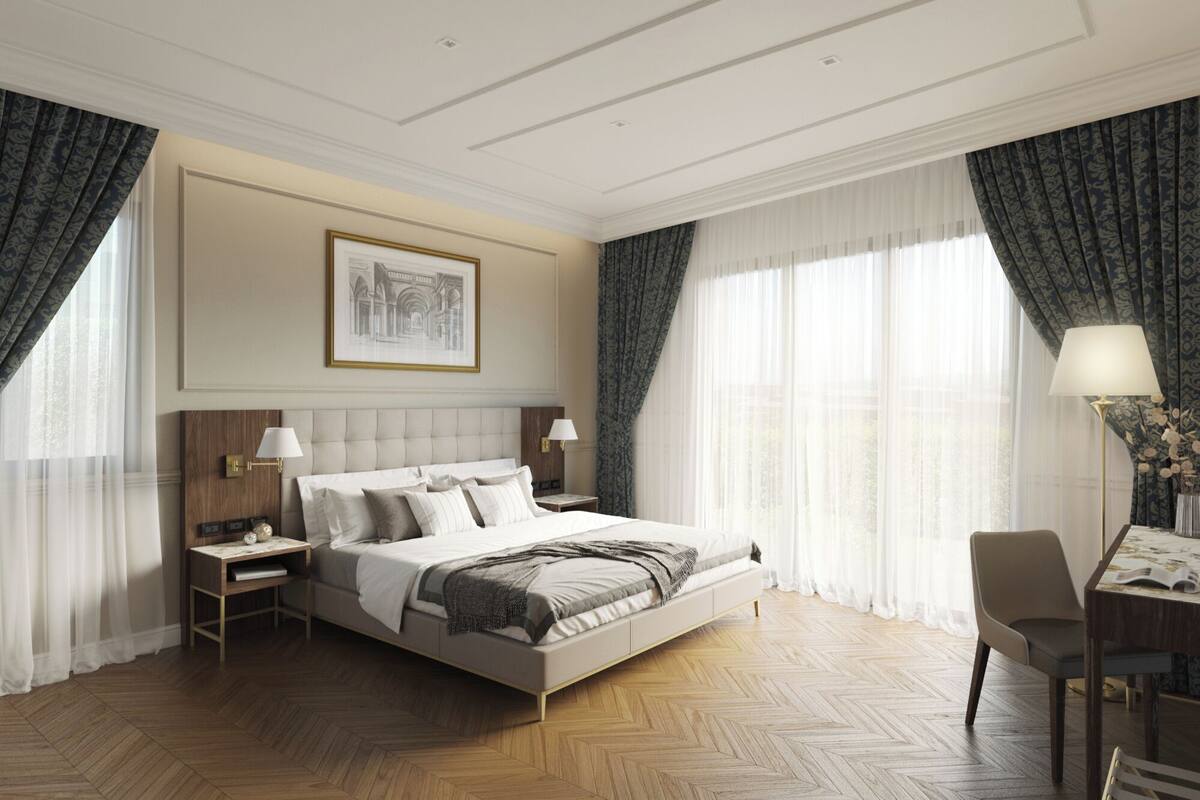 Ein Hotelzimmer mit einem großen Bett, zwei Nachttischen, einem Schreibtisch mit Stuhl und einem großen Fenster mit Vorhängen.