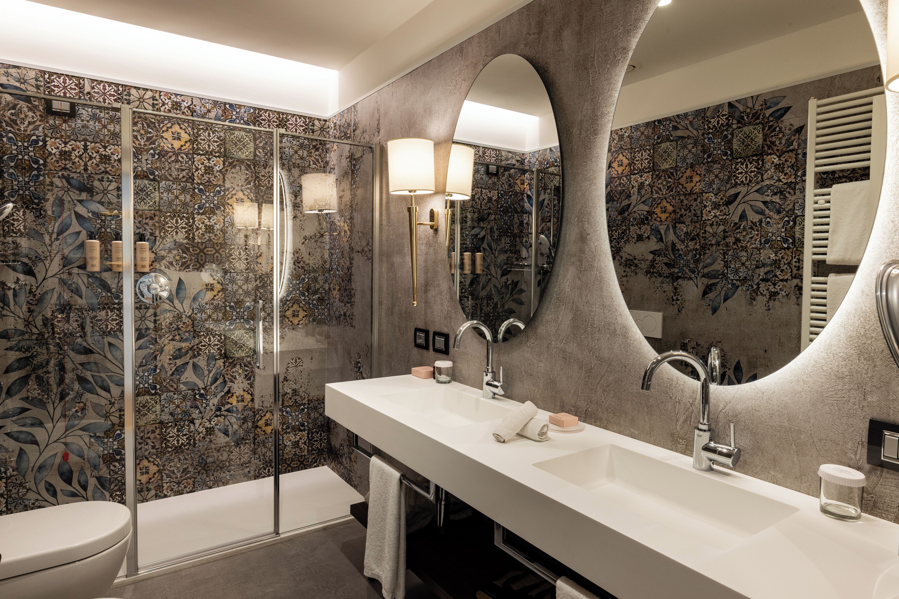 A bathroom with a large mirror, a white sink, and a shower with a glass door.