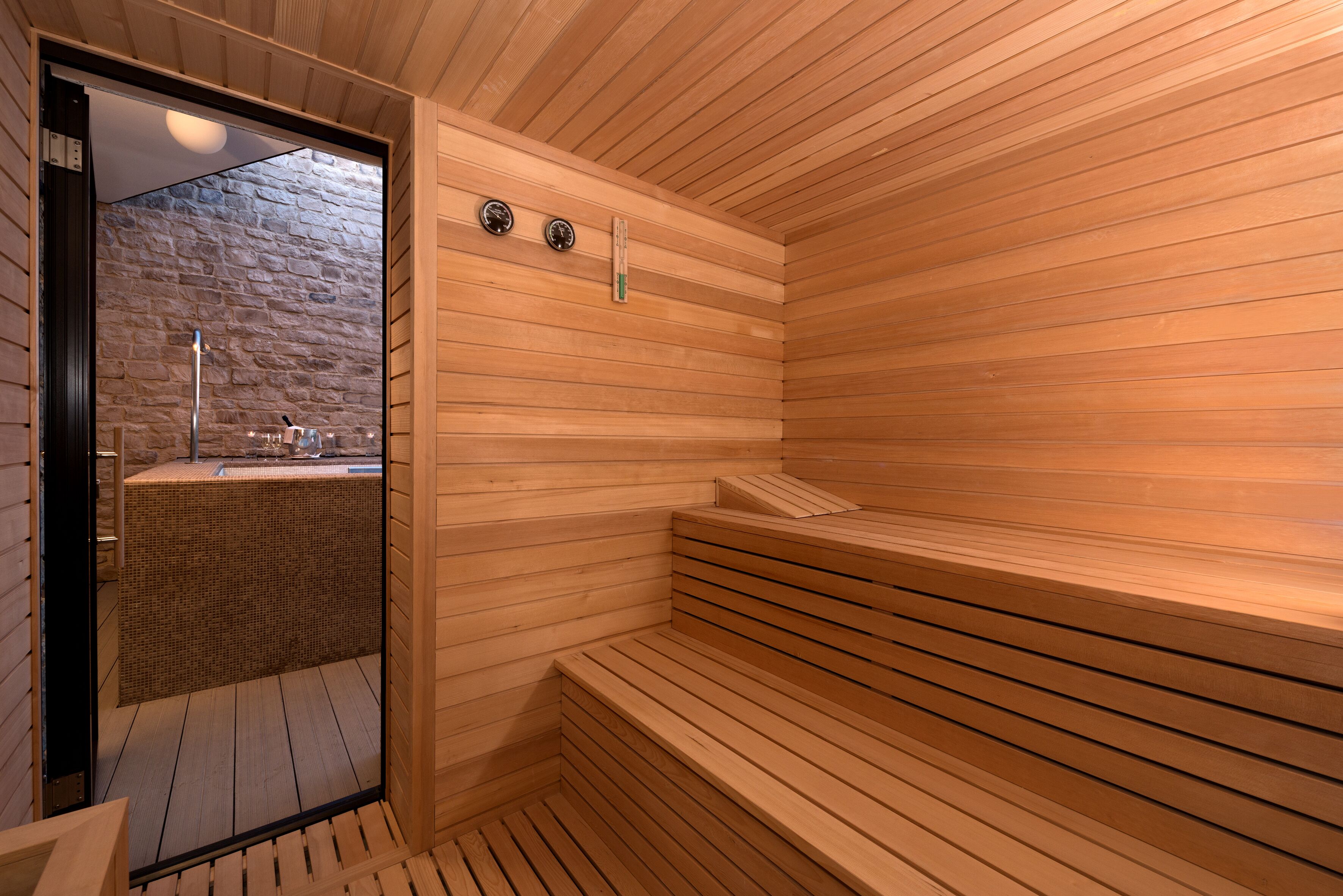 A sauna with wooden benches and a stone wall.