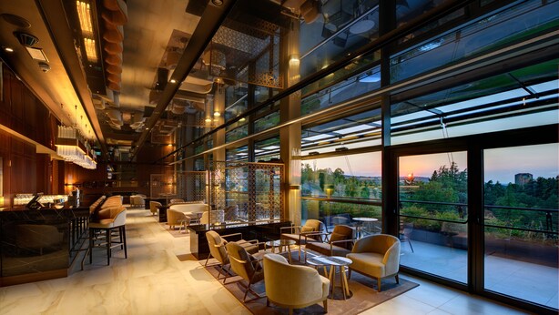 A modern interior with a bar area, seating, and large windows offering a view of the outdoors. - Palazzo di Varignana Resort & SPA (Castel San Pietro Terme)