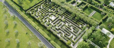 An aerial view of a meticulously landscaped garden with geometric pathways and neatly trimmed hedges.