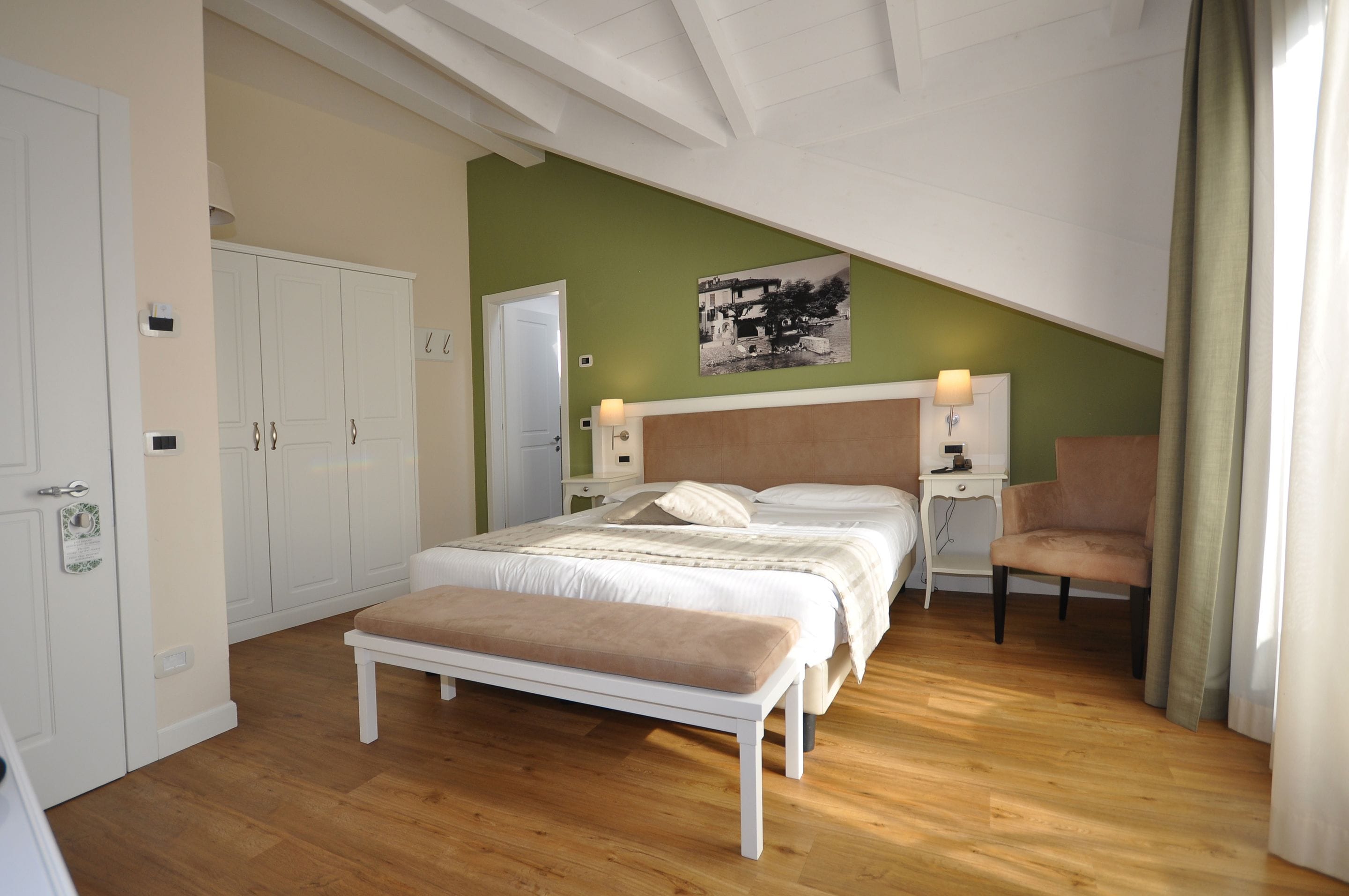 Une chambre à coucher comprenant un lit, un banc, une table de chevet, une lampe, une chaise et une porte.