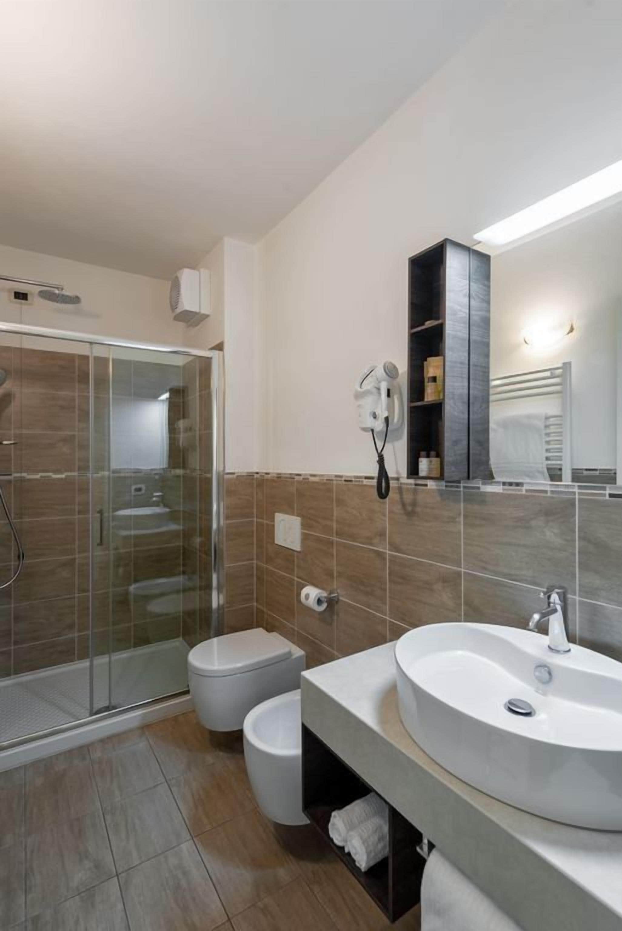 Une salle de bain moderne avec une douche à parois de verre, des toilettes, un lavabo avec un miroir et un porte-serviettes.