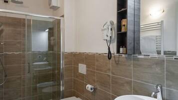 Une salle de bain moderne avec une douche à parois de verre, des toilettes, un lavabo avec un miroir et un porte-serviettes.