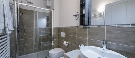 A modern bathroom with a glass-enclosed shower, a white sink, and a vanity.