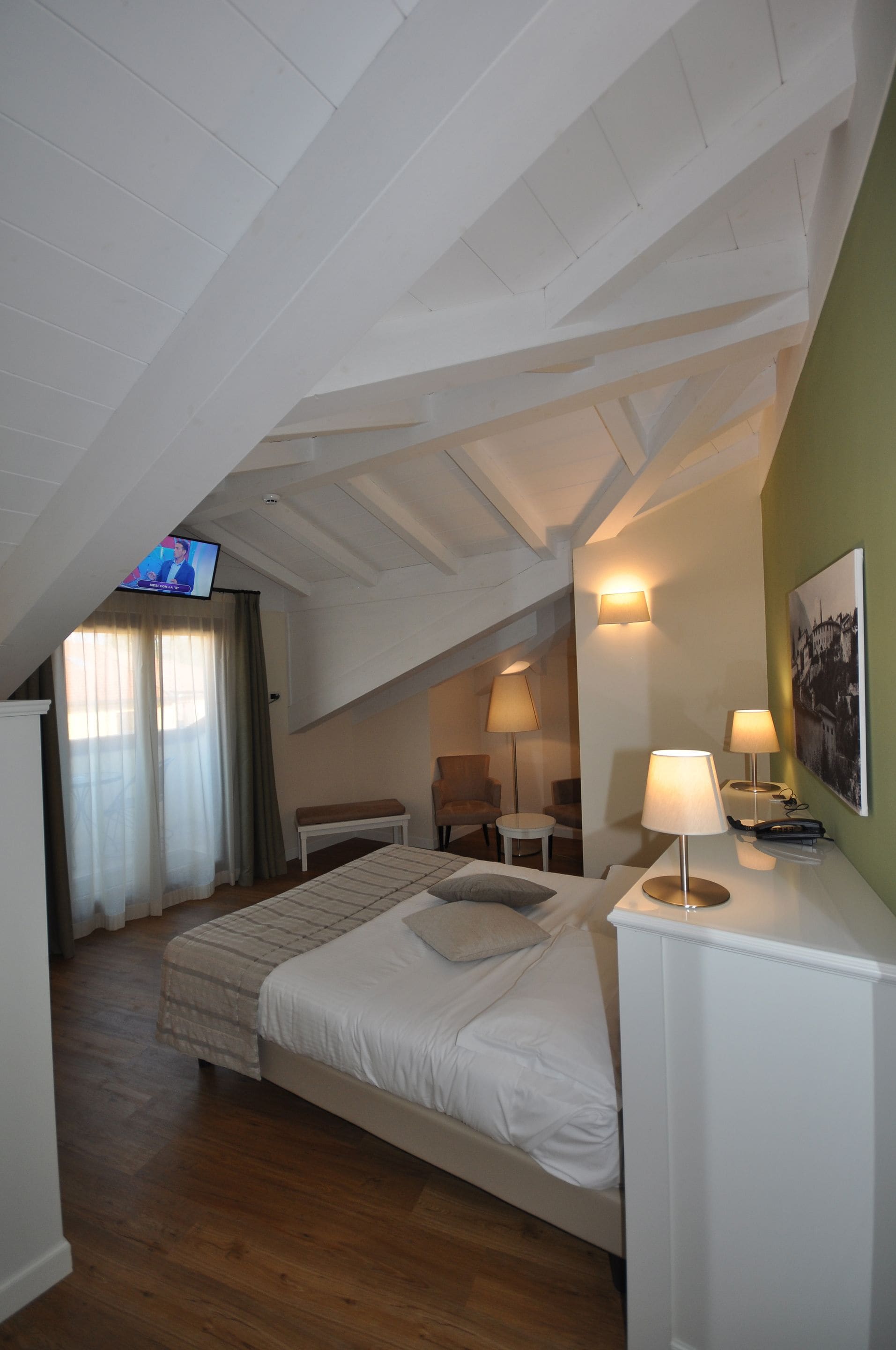 Ein Schlafzimmer mit einem Bett, Nachttischlampen, einem Fernseher und einem Bild an der Wand.