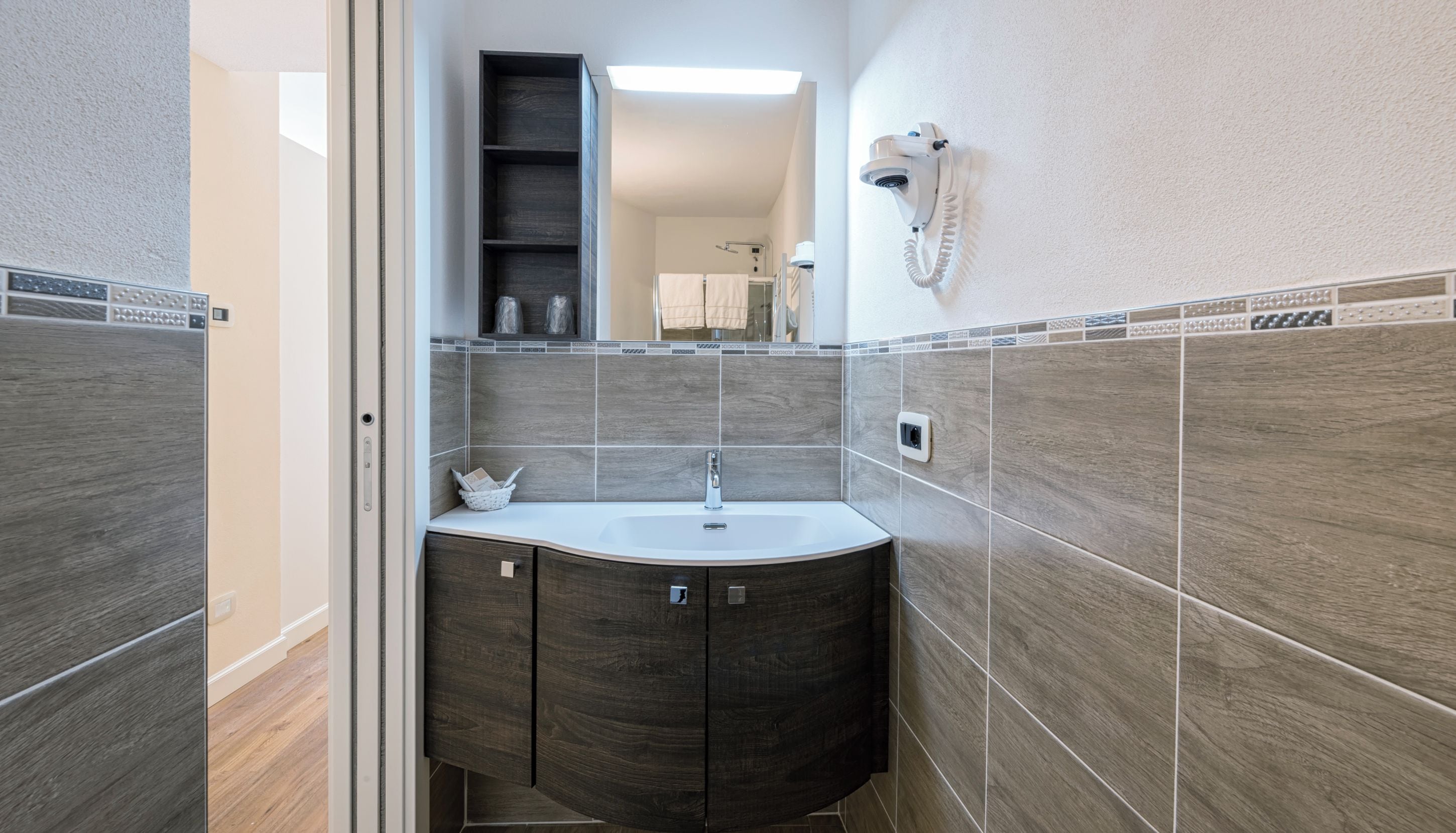Une salle de bain dotée d’un lavabo moderne, de meubles en bois foncé et de murs carrelés.