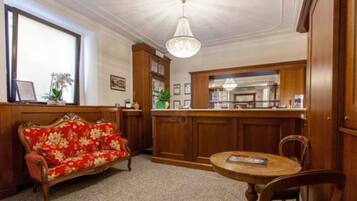 A room with a wooden sofa, a round table, and a bar area with wooden cabinets.