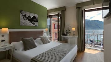 Een hotelkamer met een bed, nachtkastjes, uitzicht op zee en een balkon.