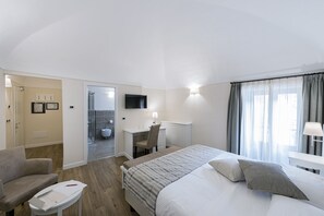 Hotellihuone, jossa on sänky, työpöytä, tuoli, sohva ja pieni pöytä.