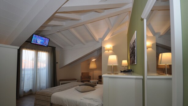 A bedroom with a bed, a television, and two lamps. - Hotel Garni Corona (Menaggio)
