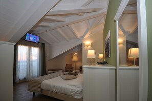 A bedroom with a bed, a television, and two lamps.
