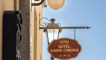 Un letrero de hotel con el nombre 'HOTEL GARNI CORONA' y un símbolo de corona.