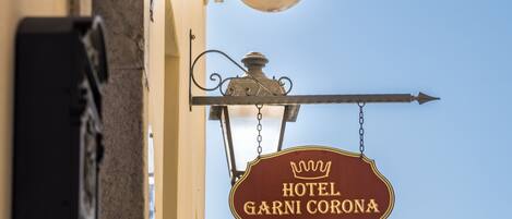 Un letrero de hotel con el nombre 'HOTEL GARNI CORONA' y un símbolo de corona.