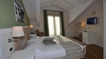 Una habitación de hotel con cama, mesita de noche, lámpara, silla, escritorio y televisión.