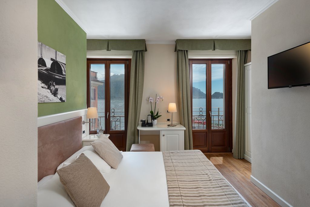 Una camera d'hotel con un letto, una scrivania, una TV e vista sul mare.