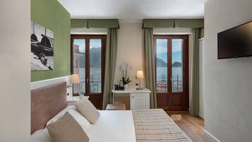Una camera d'hotel con un letto, una scrivania, una TV e vista sul mare.