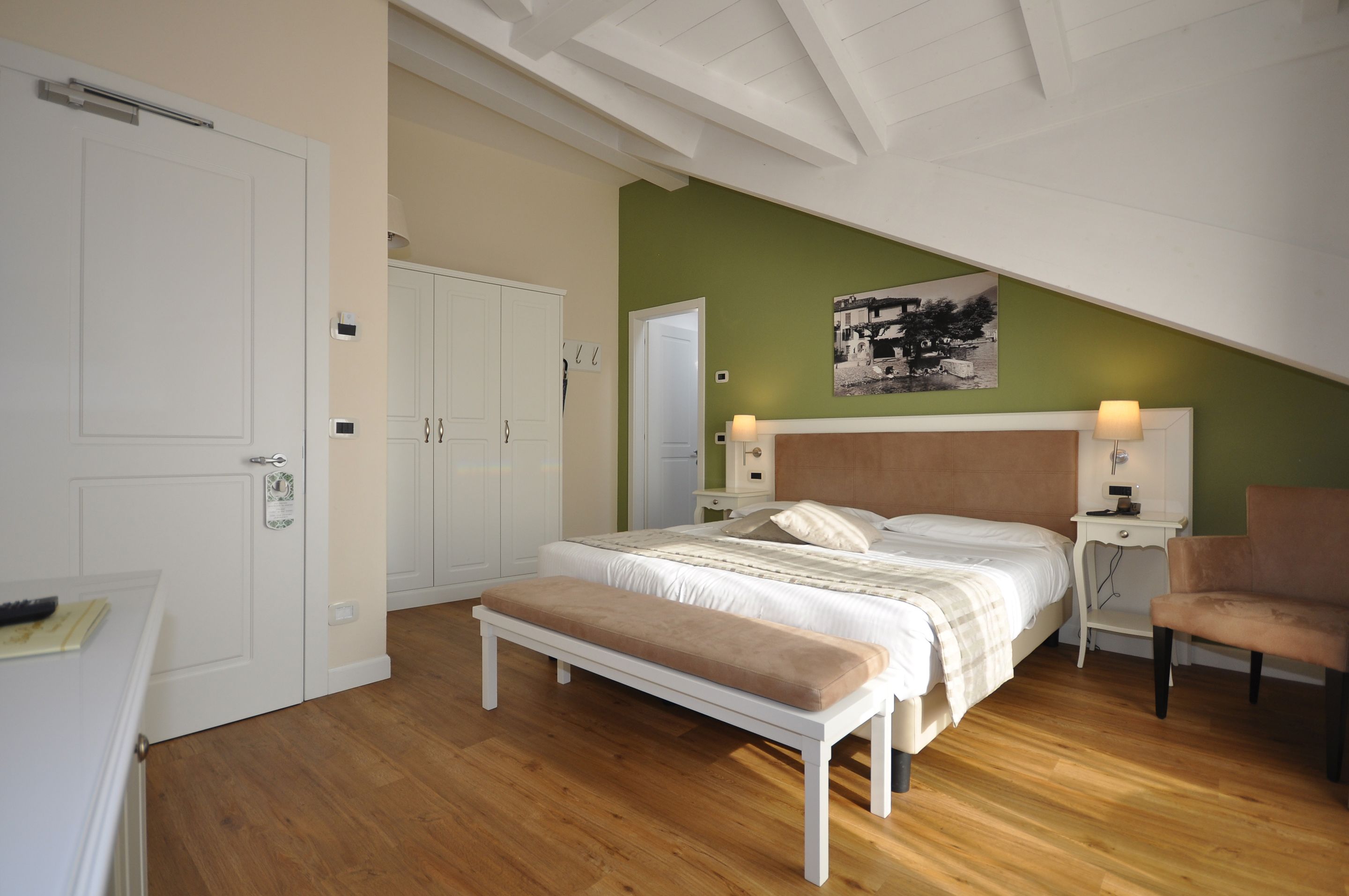 Een slaapkamer met een bed, een bankje, nachtkastjes en een stoel.