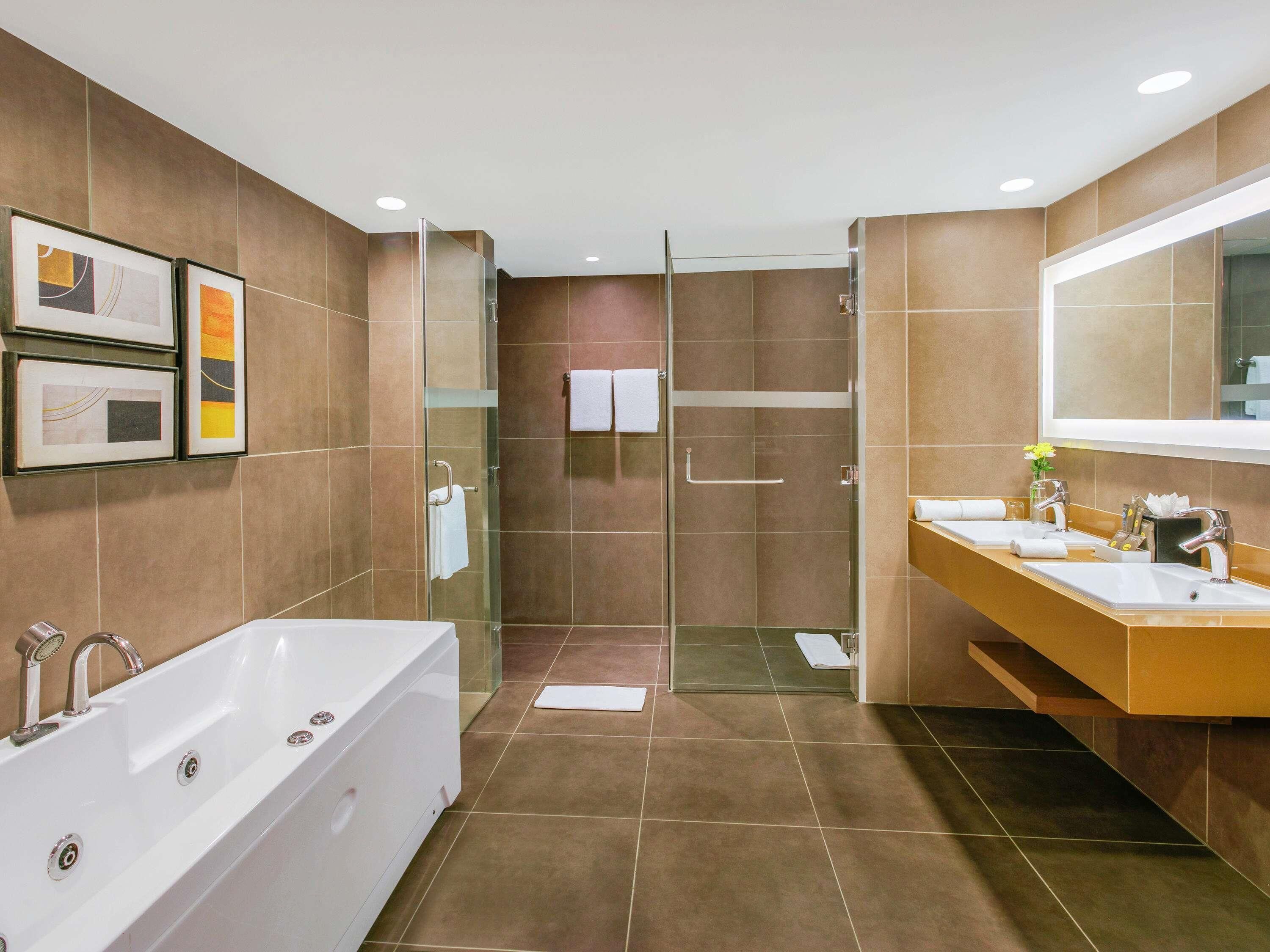 Une salle de bain moderne dotée d’une grande baignoire, d’une douche à l’italienne et d’un meuble-lavabo avec deux vasques.
