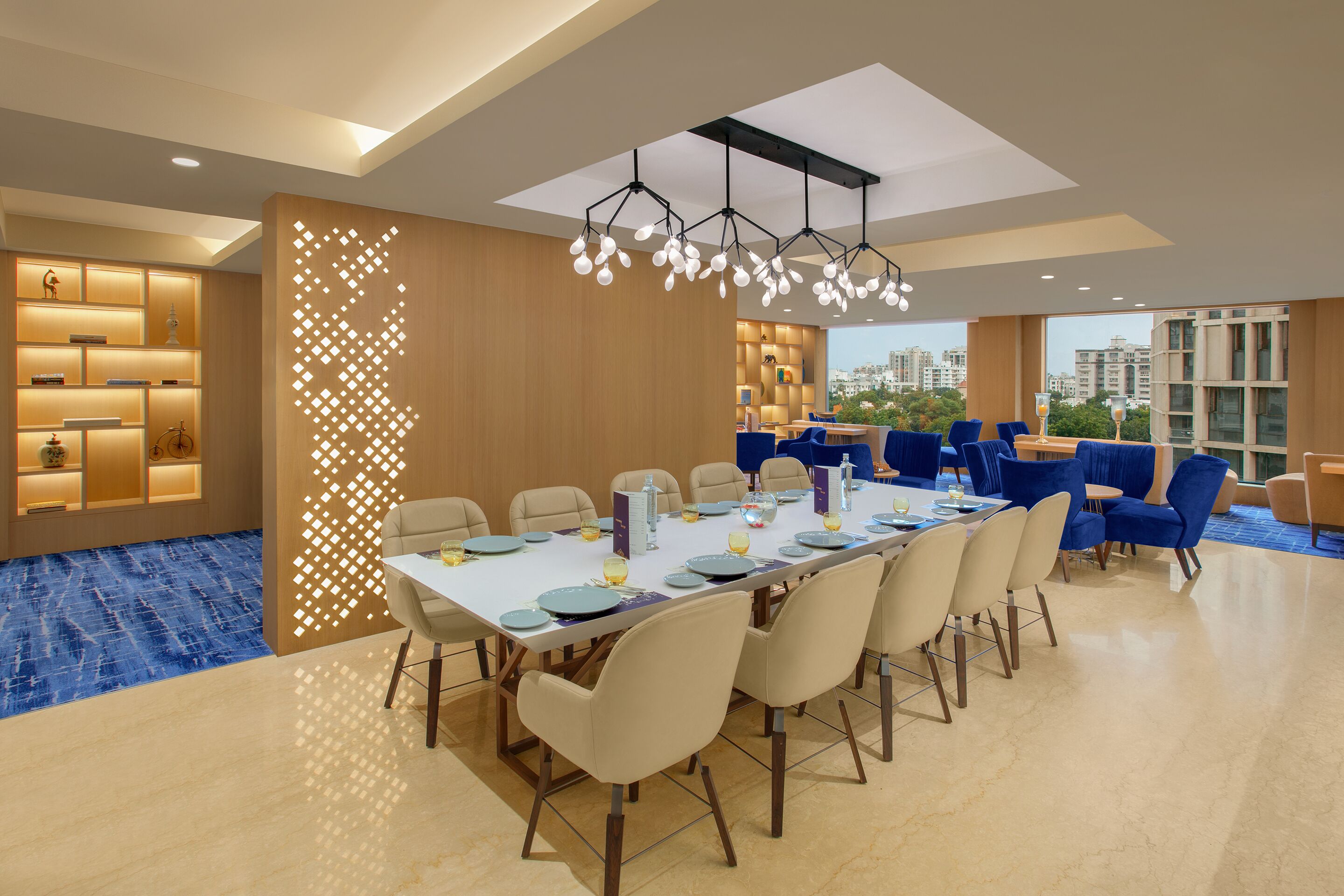 A modern dining area with a long table, chairs, and a decorative light fixture.