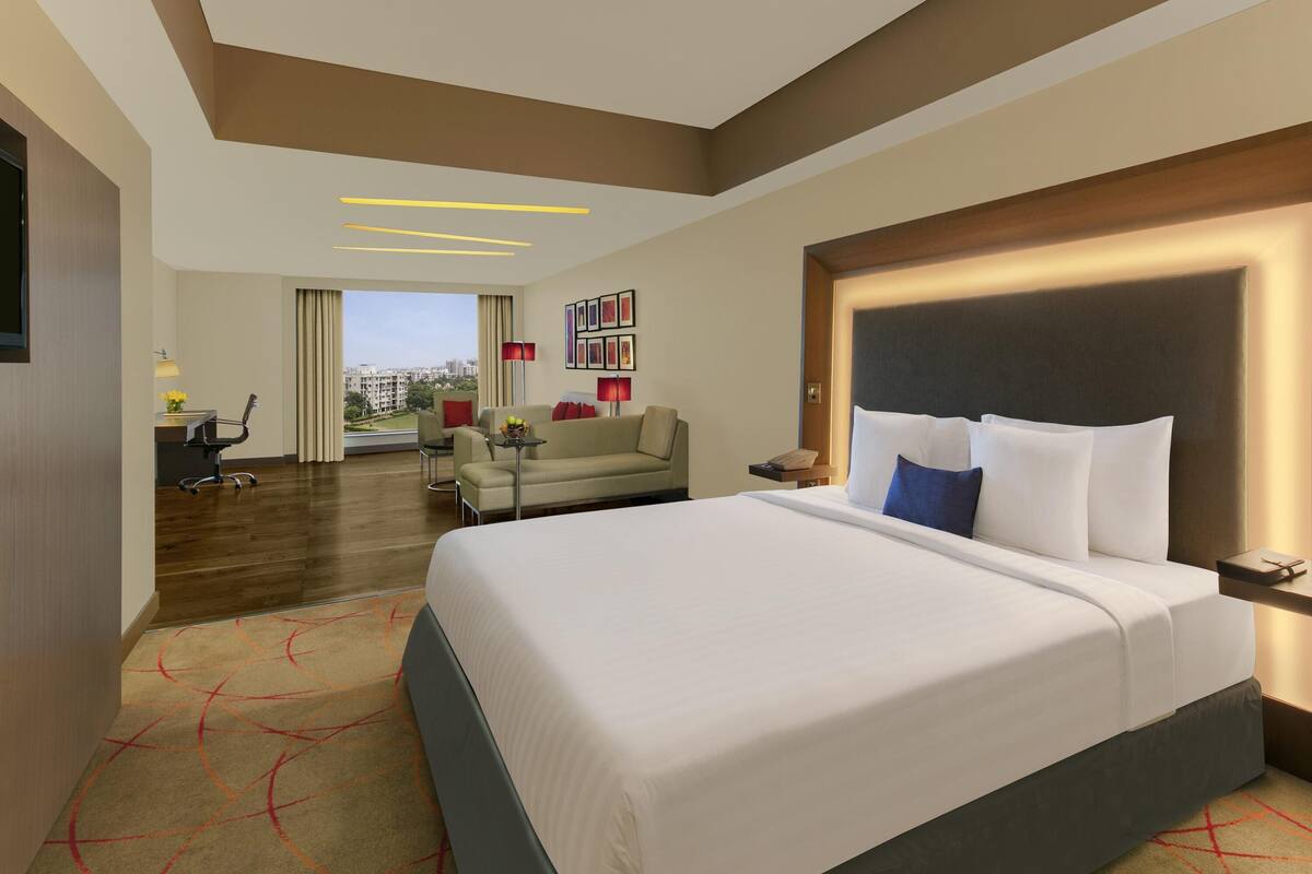 Une chambre d’hôtel moderne dotée d’un grand lit, d’un bureau, d’un canapé et offrant une vue sur la ville.