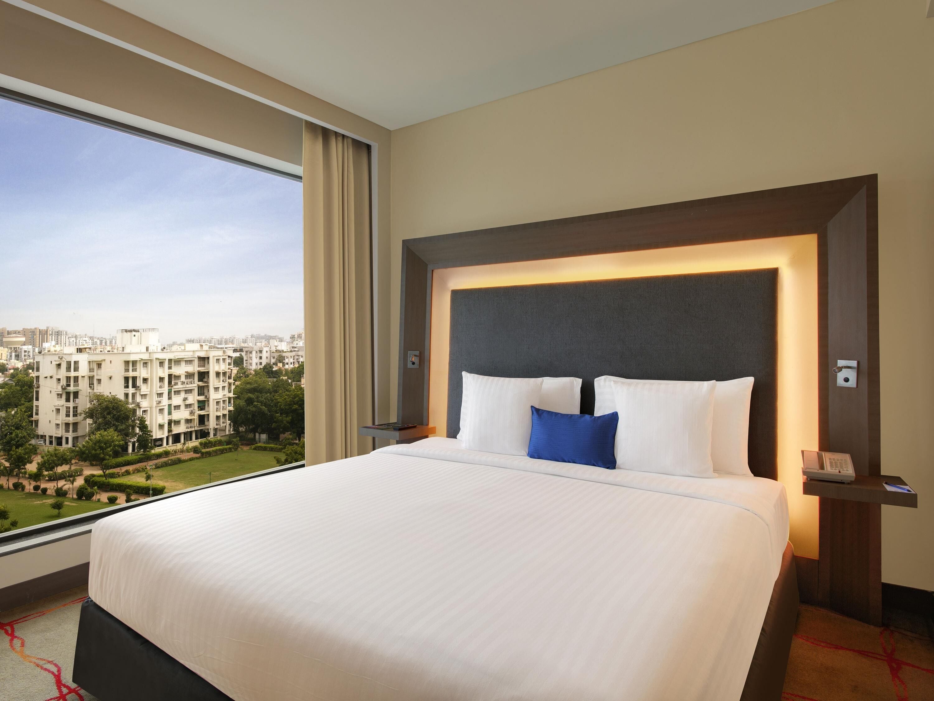Une chambre d’hôtel avec un grand lit, une vue sur la ville et un design moderne.