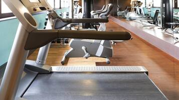 Un gimnasio con cintas de correr, bicicletas estáticas y máquinas de pesas.