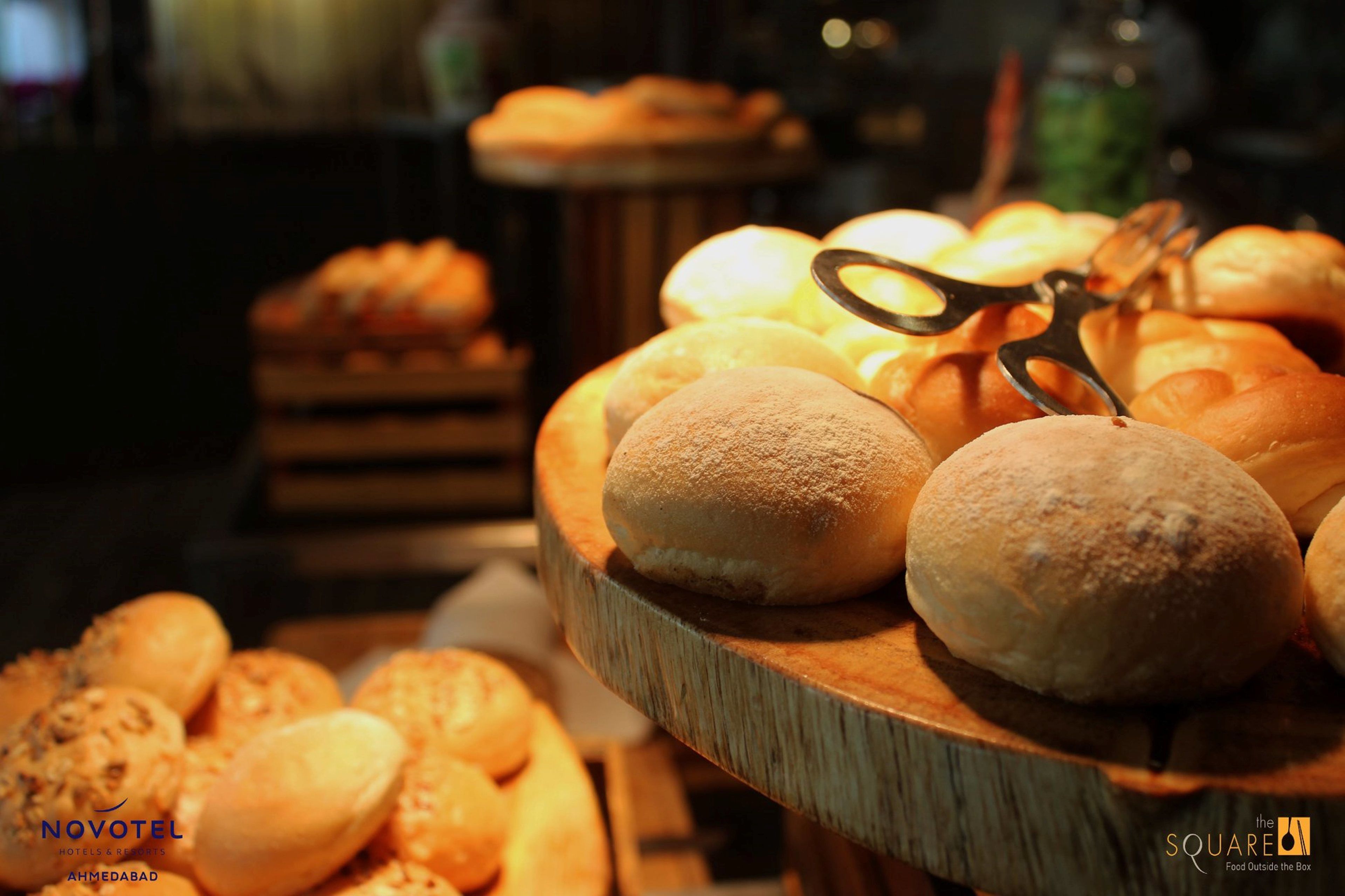A variety of breads and pastries displayed on a wooden board with a pair of scissors.