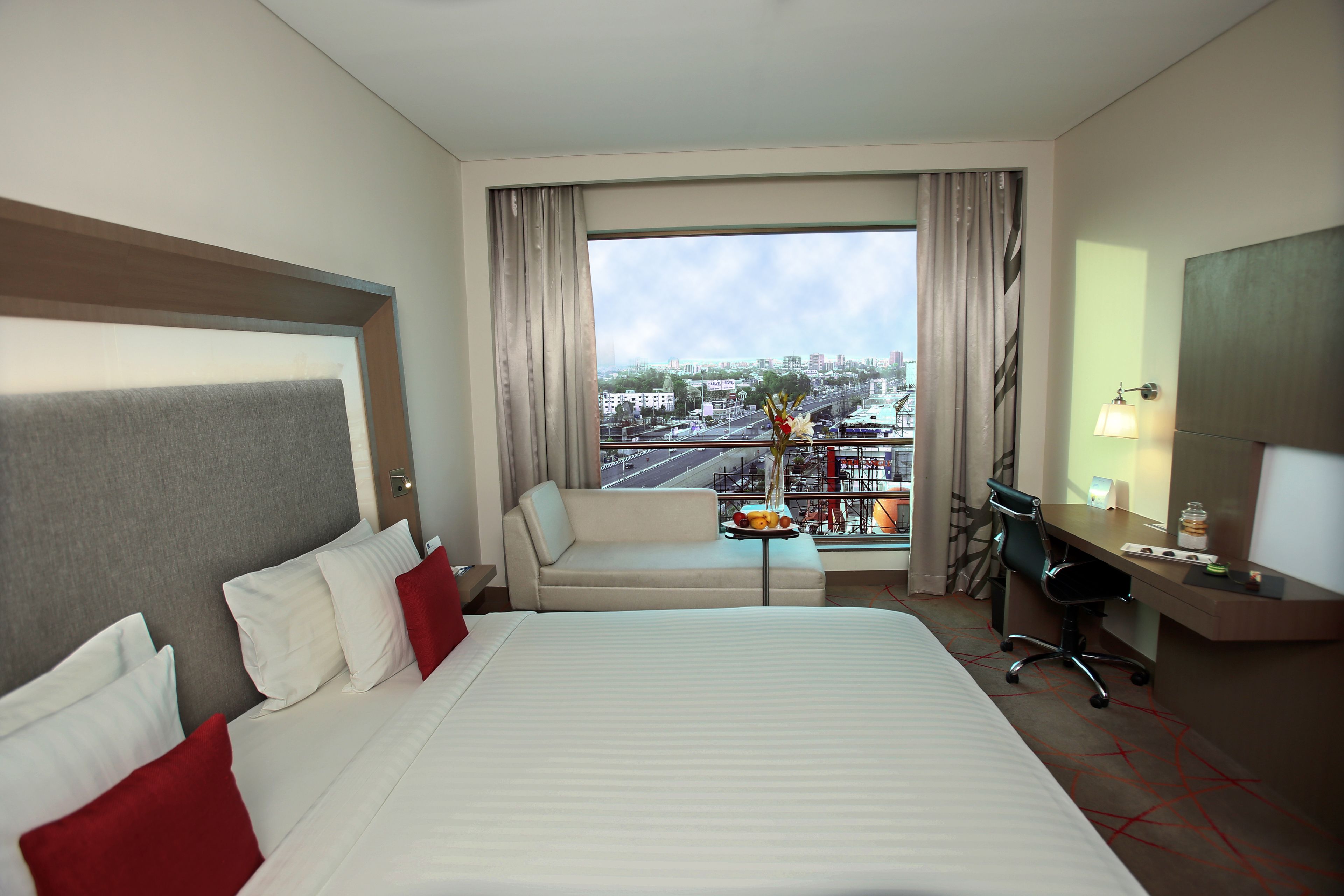 Une chambre d’hôtel avec un grand lit, un canapé, un bureau et une vue sur le paysage urbain.