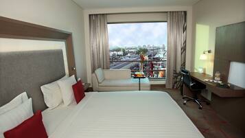 Habitación de hotel con una cama grande, un sofá, un escritorio y vistas a la ciudad.
