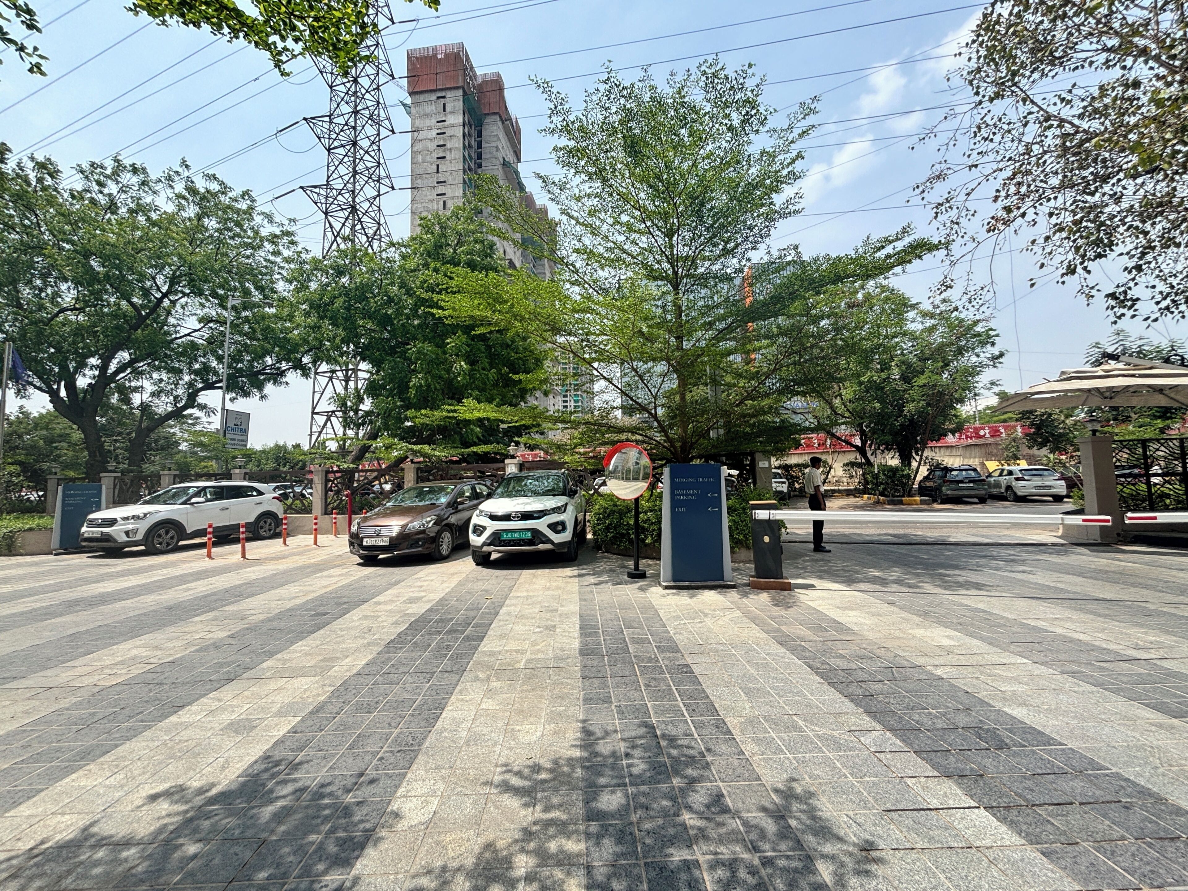 A parking area with cars, a signpost, and a tall building in the background.
