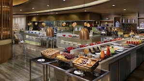 Zona de bufé con diversas opciones de comida y una decoración interior moderna.