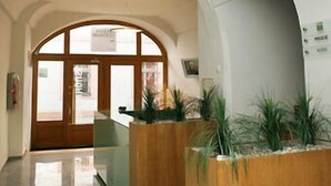 A spacious hallway with arched ceilings and a wooden planter with plants. - Hotel v Centru (Ceske Budejovice)