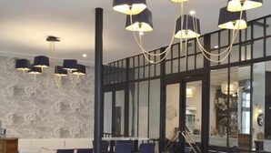 Een moderne eetruimte met witte tafels en stoelen, wanden met zwart-wit patronen en een groot raam met uitzicht.