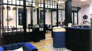 Een salon met een receptiebalie, stoelen en een blauwe bank.