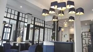 Een modern interieur met een receptiebalie, een zithoek en een kroonluchter.