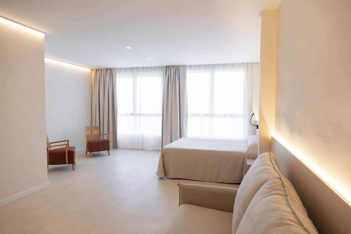 Ein modernes Hotelzimmer mit einem großen Bett, einer Couch, einem Sessel und einem Schreibtisch.